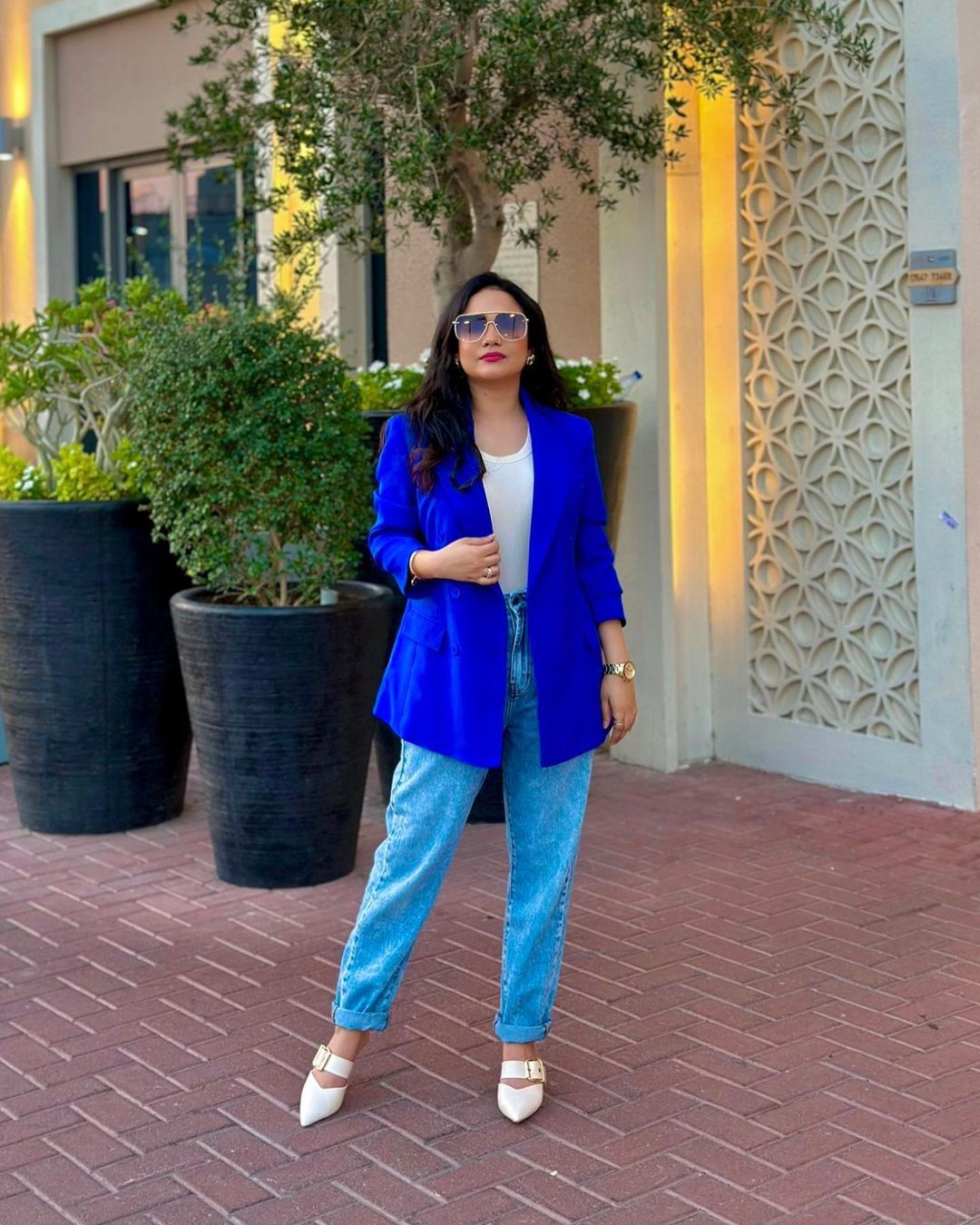 Aisha Omair, a UAE-based digital creator, pharmacist, and freelance marketer, stands confidently in front of a vibrant backdrop. She exudes creativity and determination, symbolizing her multifaceted journey and accomplishments.