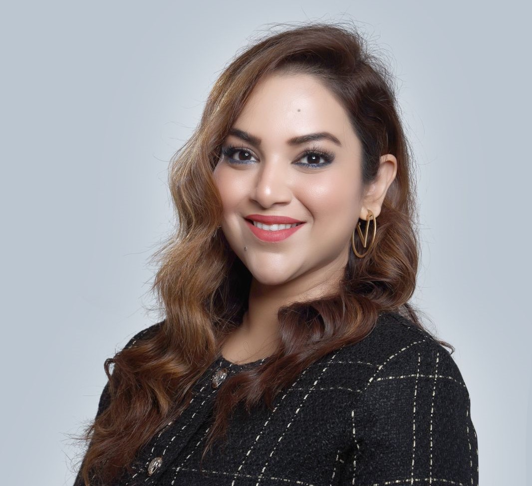 A photograph of Sughra Banga, a successful entrepreneur in Dubai's real estate industry. She exudes confidence and determination, standing in a modern urban setting that represents the thriving city of Dubai. The image captures her passion for real estate, reflecting her dedication to helping clients find their dream homes and her entrepreneurial spirit.