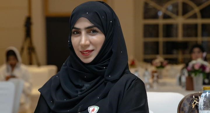 Dr. Aysha Ibrahim Al Dhaheri stands confidently in a well-lit room, dressed professionally. She holds a certificate in her hand, symbolizing her academic achievements and commitment to education. The background features a bookshelf with neatly arranged books, signifying knowledge and expertise. A subtle smile on her face reflects her positive and empowering personality. The image exudes professionalism and determination, capturing Dr. Aysha's inspiring presence.