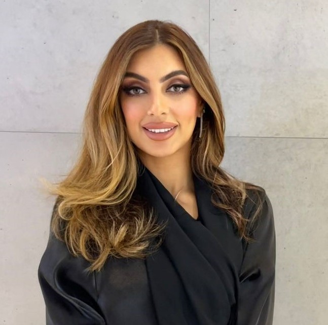 Engineer Marwa Al Mamari, the First Emirati Aerospace Engineer, standing confidently in front of a backdrop of aviation technology. She is holding a document, symbolizing her academic achievements and expertise in aviation safety and artificial intelligence. The image captures her passion for advancing aviation safety and empowering women in STEM fields.