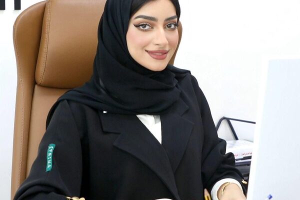 A professional portrait of Khulood Al Khudoori, a distinguished lawyer and legal consultant. She exudes confidence and determination, symbolizing her commitment to the field of law and justice. In the background, there are subtle legal motifs, emphasizing her role in the legal landscape.